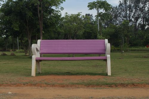 Free A vibrant purple bench in a lush green park, ideal for relaxation and nature walks. Stock Photo