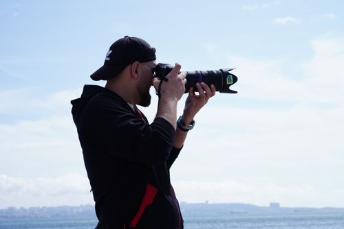Free A man focuses his camera on the horizon, capturing a scenic view by the Caspian Sea in Baku, Azerbaijan. Stock Photo