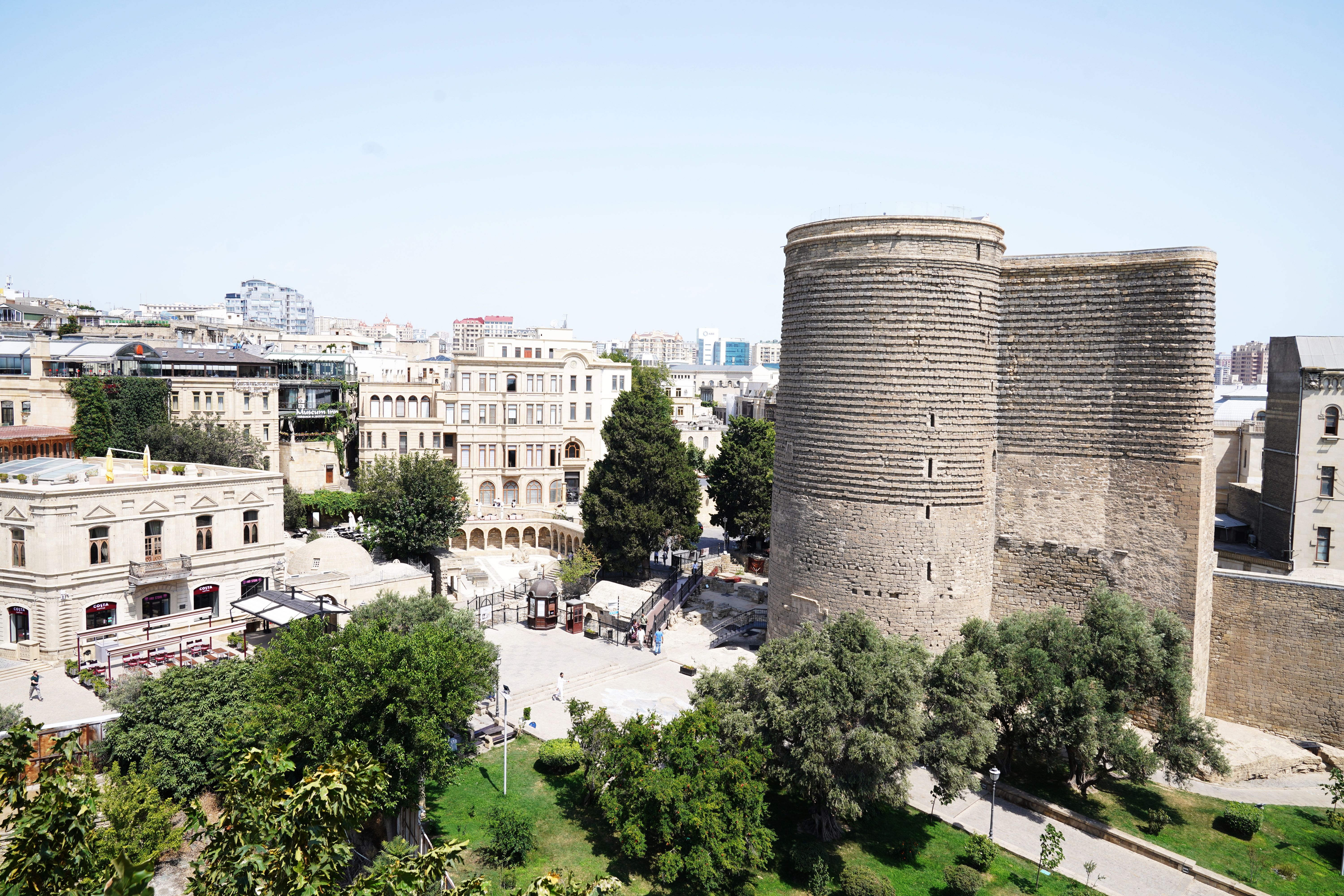 Aerial view of Maiden Tower and the historic architecture of Baku's Old City under a clear sky.