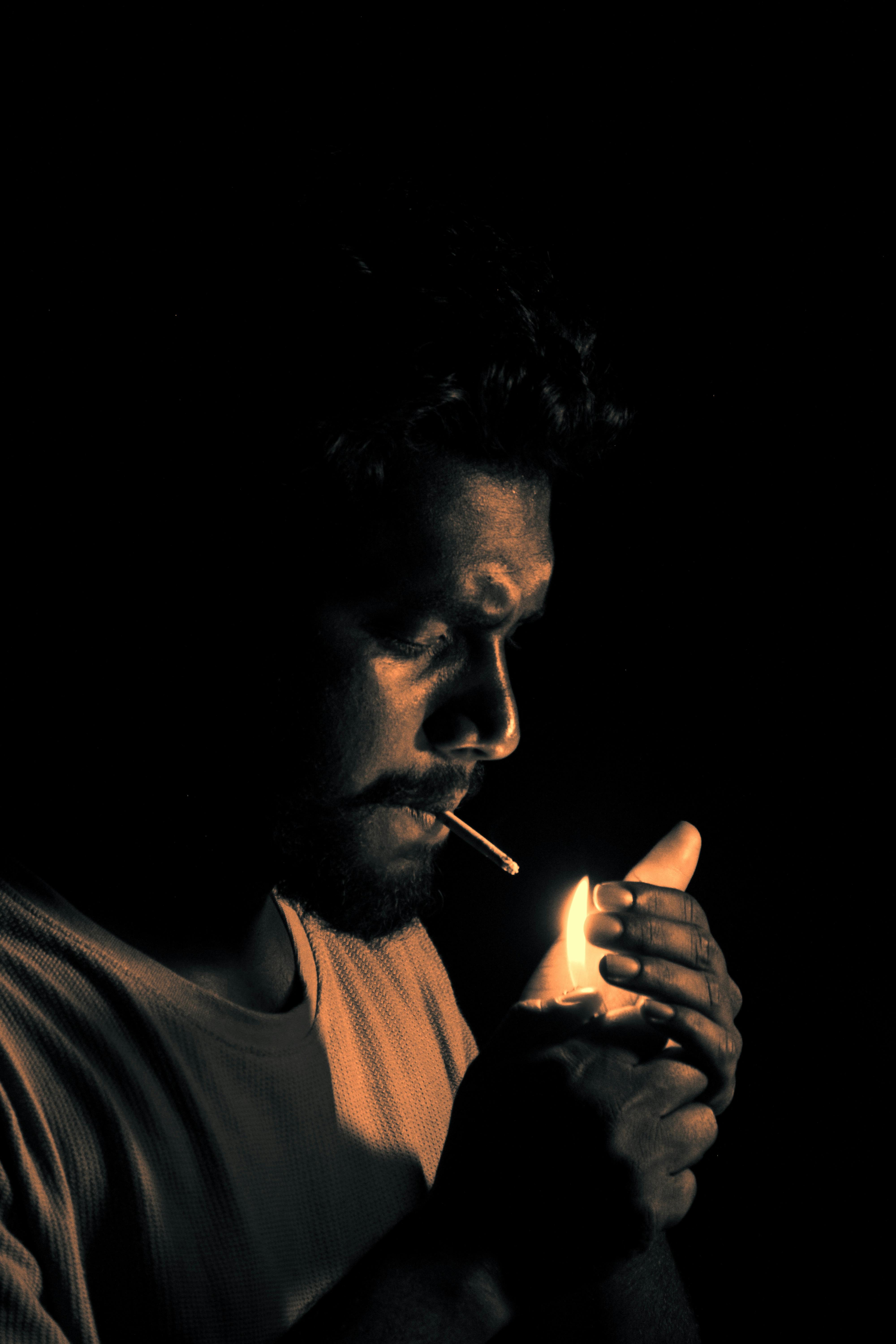 Ücretsiz Bir adamın kibritle sigara yaktığı dramatik, loş ışıklı portre. Stok Fotoğraflar