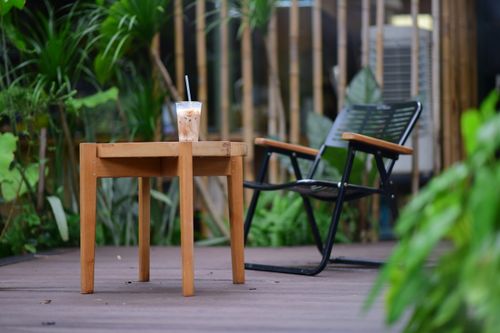 Free Serene outdoor cafe setting featuring a refreshingly iced coffee on a wooden table. Stock Photo