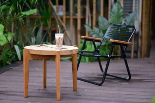 Free A relaxing patio scene with a wooden table, metal chair, and iced coffee, perfect for unwinding. Stock Photo