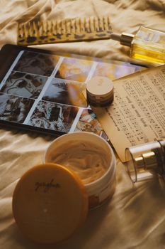 Aesthetic flat lay of skincare products, tablet, and sheet music on a bed, perfect for lifestyle or health themes.