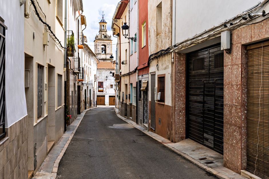 Una pintoresca calle en Chelva, España, que muestra la arquitectura tradicional y la torre de la iglesia.