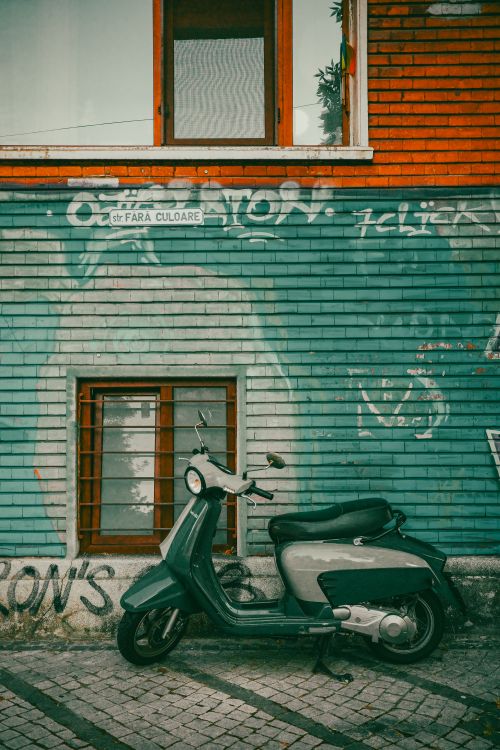 Free A vintage scooter parked against a graffiti-covered wall in Bucharest, Romania. Stock Photo