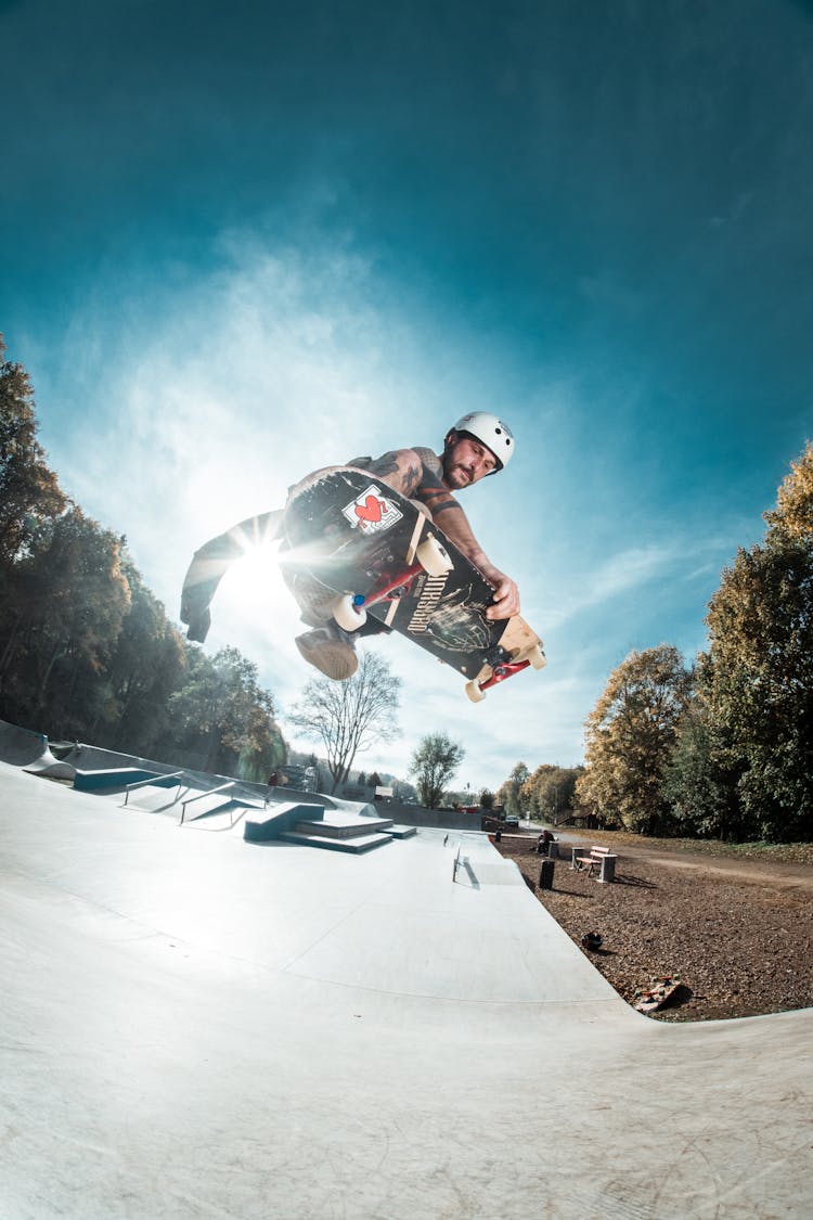 Man Skateboarding On Ramp Under Blue And White Sky