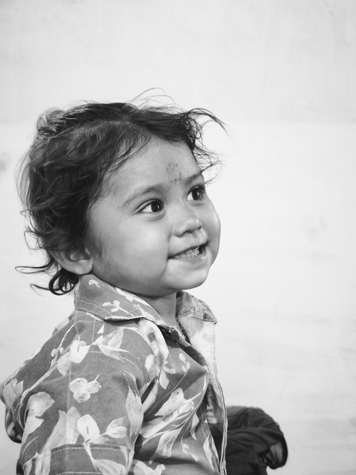 Free Black and white portrait of a smiling child in a floral shirt, conveying innocence and joy. Stock Photo