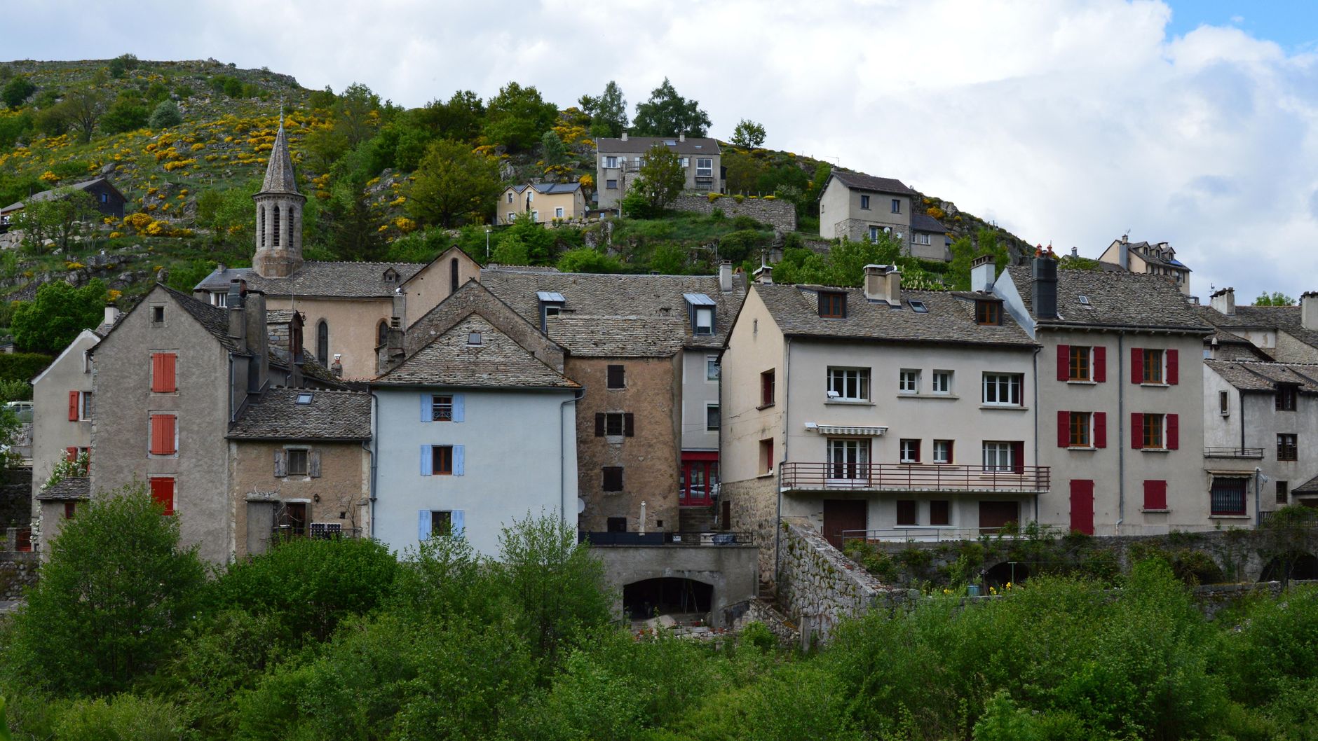 Picturesque village scene in Pont de Montvert, France showing classic European architecture against a lush hillside.
