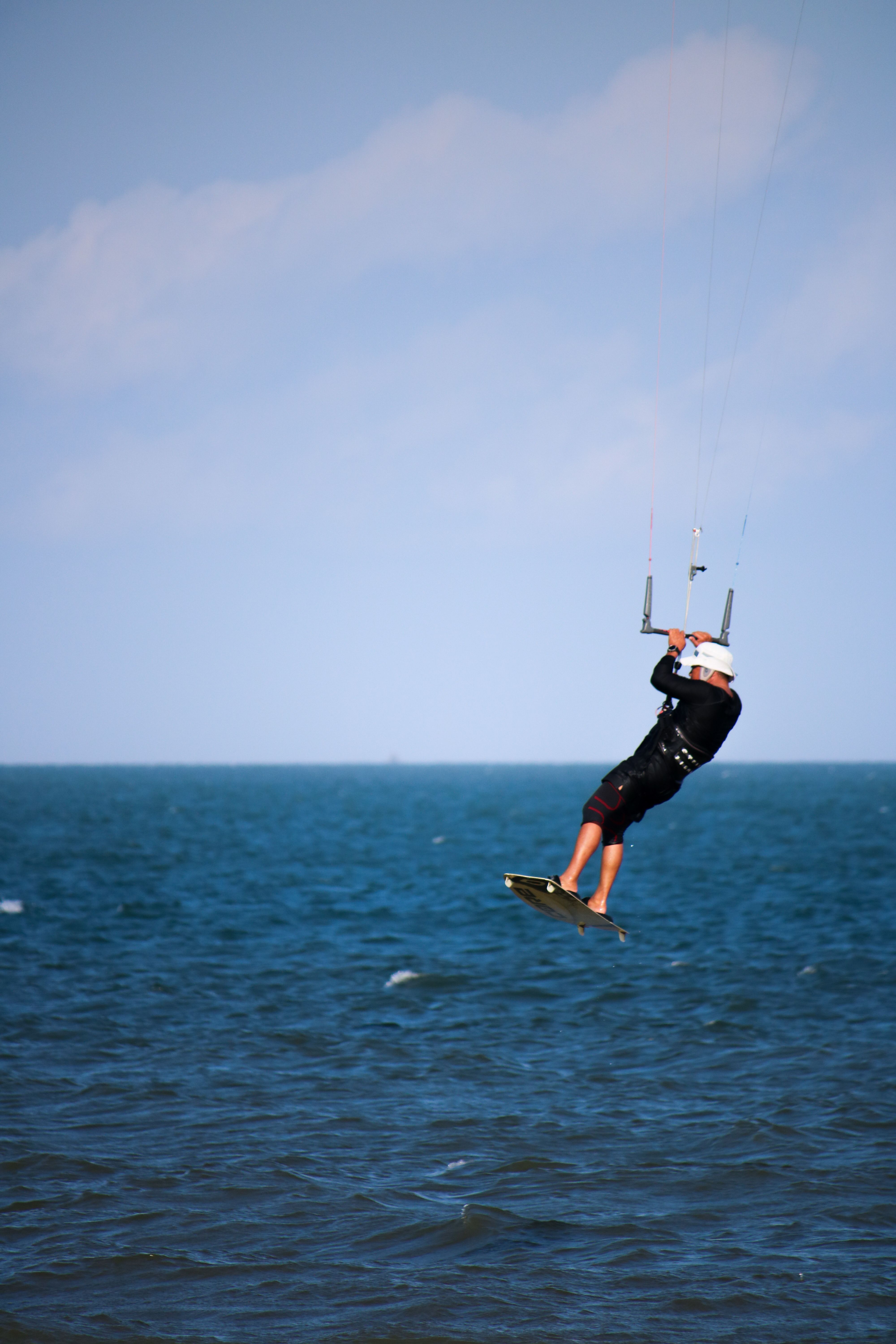 Dynamic kitesurfer soaring above the clear ocean water in Vietnam, capturing the thrill of extreme sports.