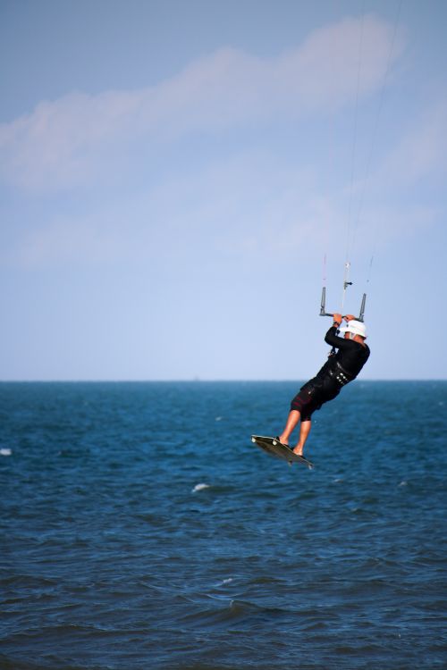 Free Dynamic kitesurfer soaring above the clear ocean water in Vietnam, capturing the thrill of extreme sports. Stock Photo
