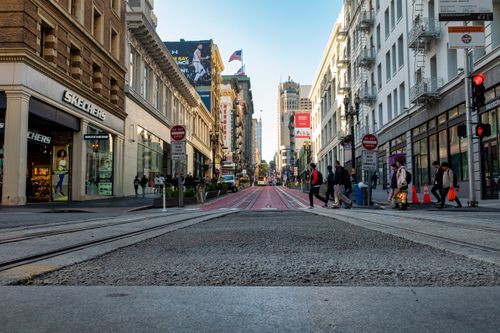 Free A lively street in San Francisco with people crossing near iconic buildings and shops. Stock Photo