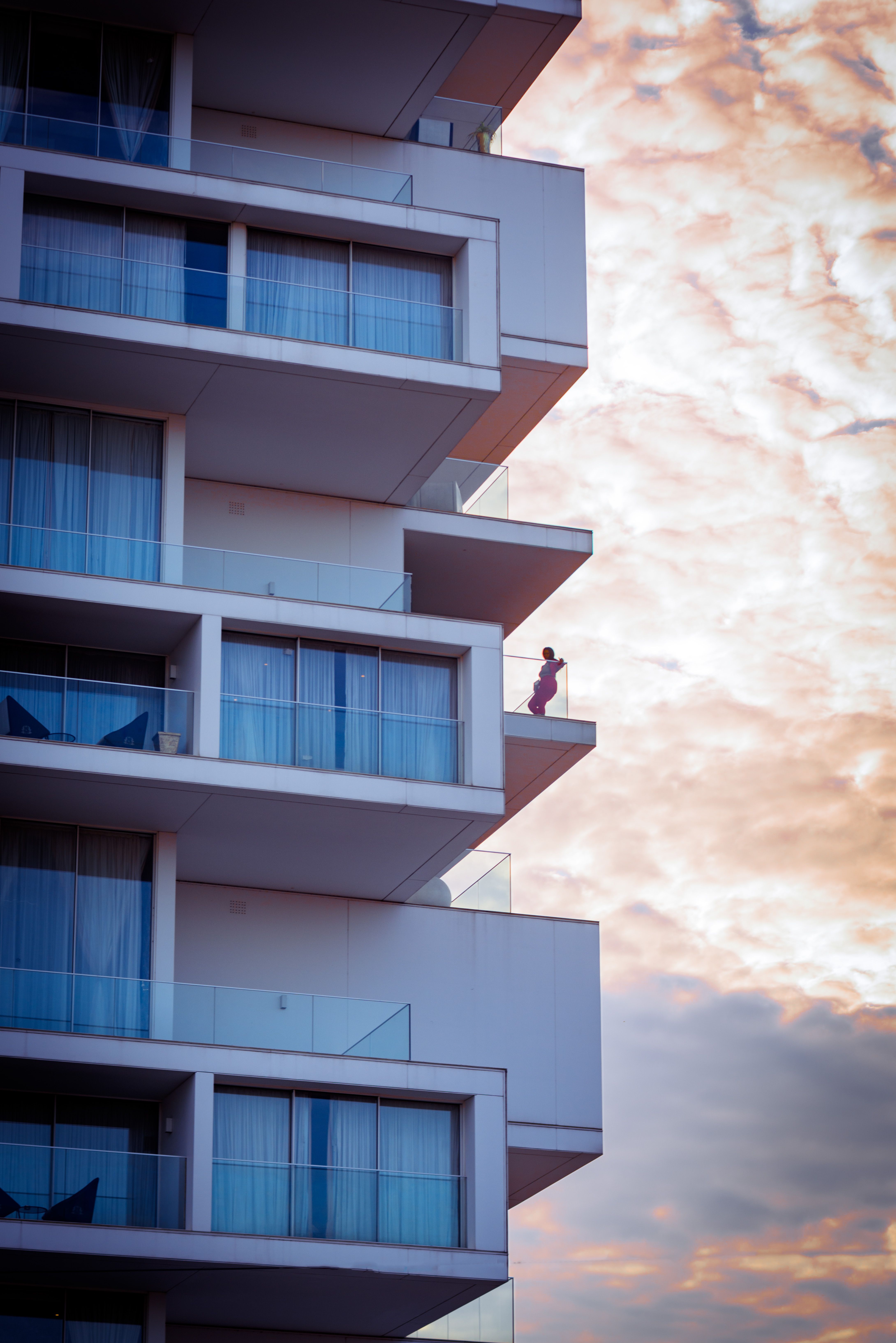 Modern Apartment Building at Sunset with Person on Balcony · Free Stock ...