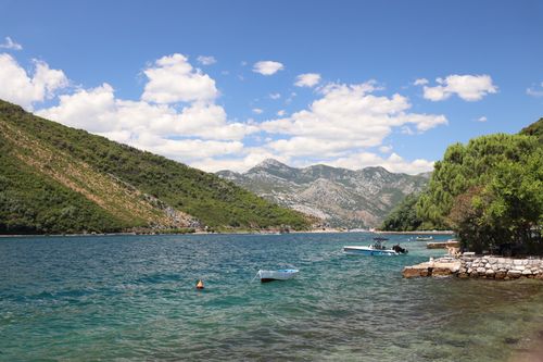 Free Serene bay with clear waters, boats, lush mountains, and blue skies. Stock Photo
