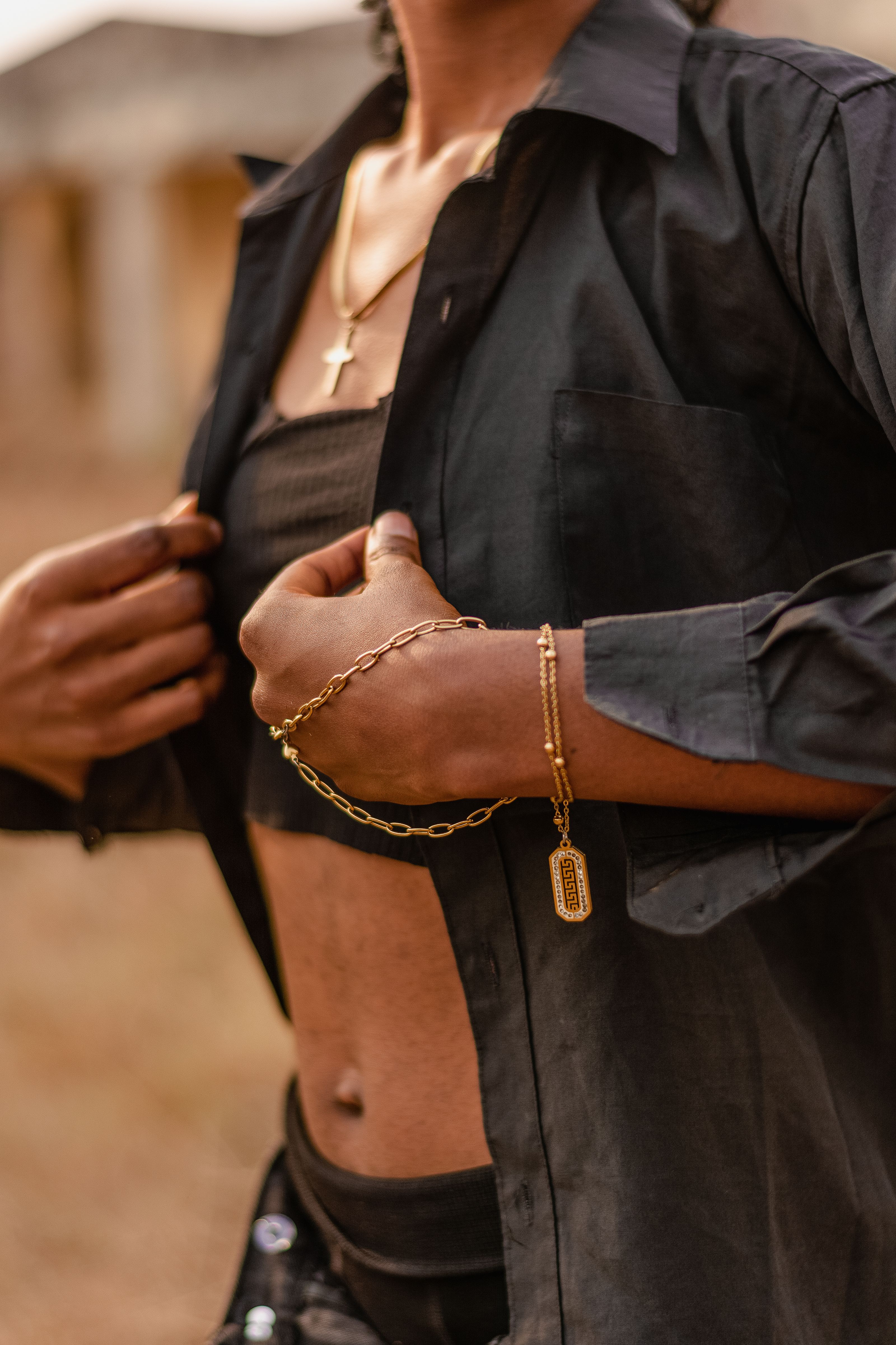 Close-up de uma mulher fashion em traje preto com joias douradas elegantes ao ar livre.