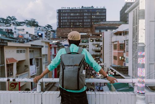 Free A person with a backpack gazes at a busy urban street from a high vantage point, capturing city life. Stock Photo