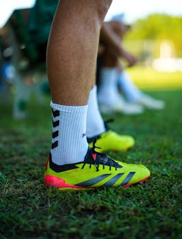 Bright football boots on green grass during a sunny day practice.