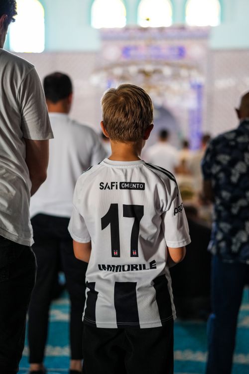 Free Child wearing a Beşiktaş jersey inside a mosque with others. Stock Photo