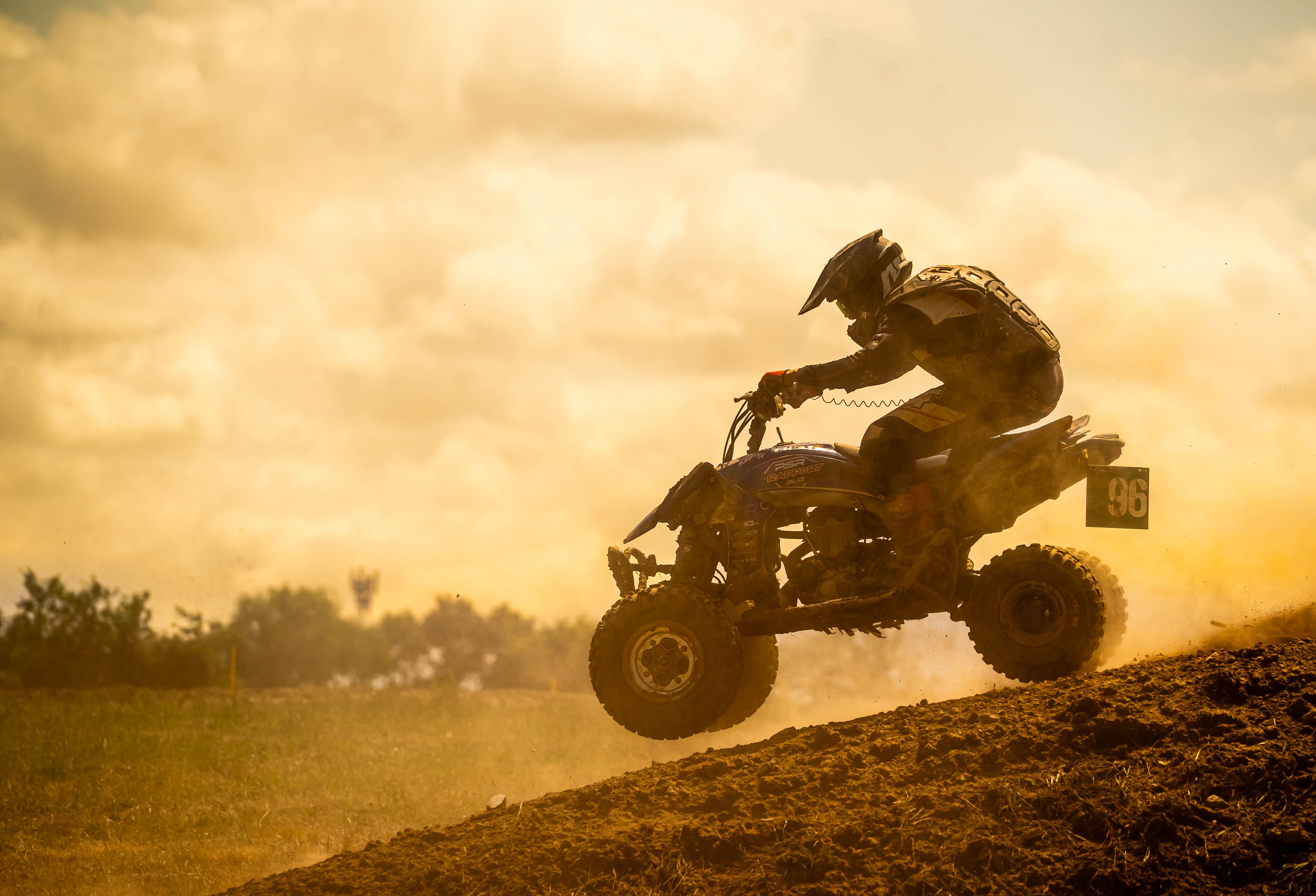Exciting motocross action as a rider speeds uphill, silhouetted against a sunset.