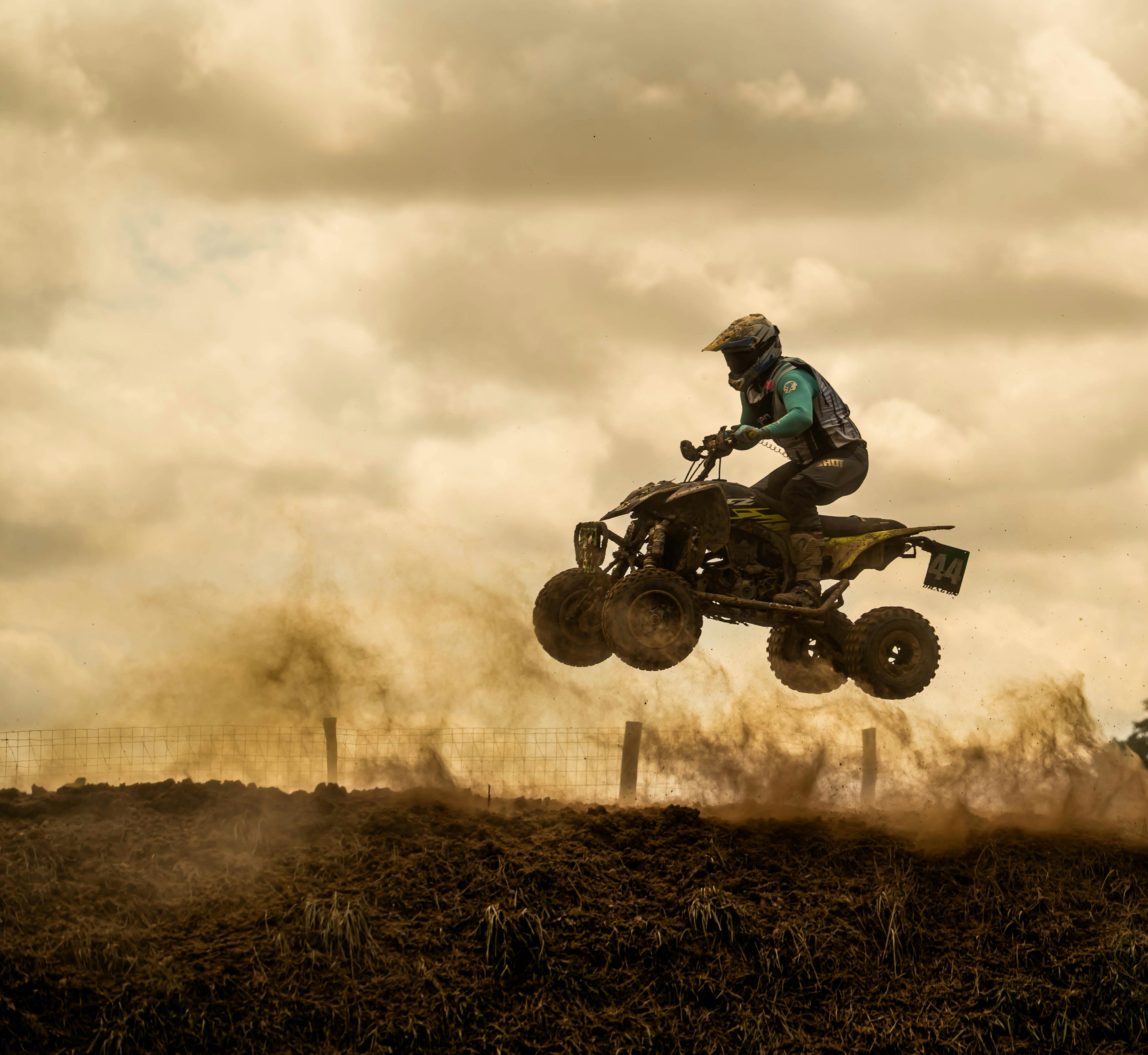 Dramatic capture of a motorcyclist performing an exciting ATV jump on a dirt track. Action-packed scene.