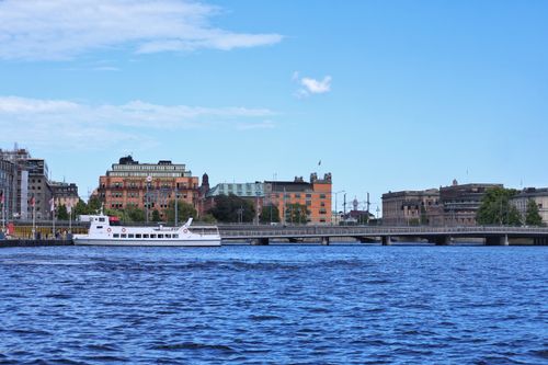 Free Enjoy a peaceful scene of Stockholm's waterfront featuring a passenger boat and historic buildings. Stock Photo