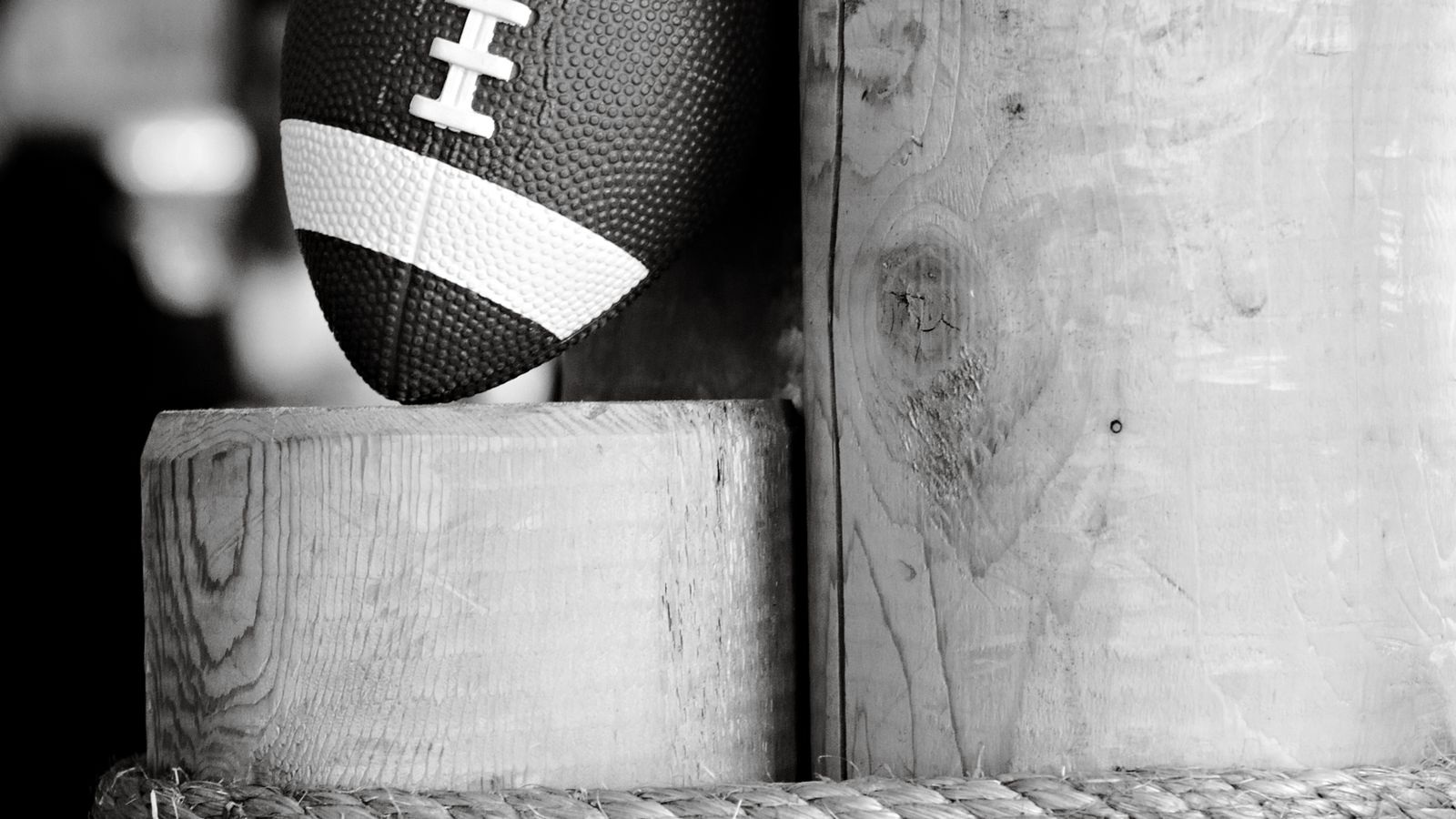 Black-and-white photo of a football resting between two rough wooden posts tied with rope, with no people in the frame, a real stock photo that echoes the makeshift field where Marines played the Mosquito Bowl on Guadalcanal