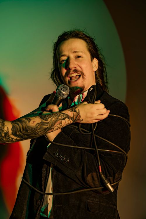 Free A charismatic singer performs passionately with a microphone under dramatic lighting. Stock Photo