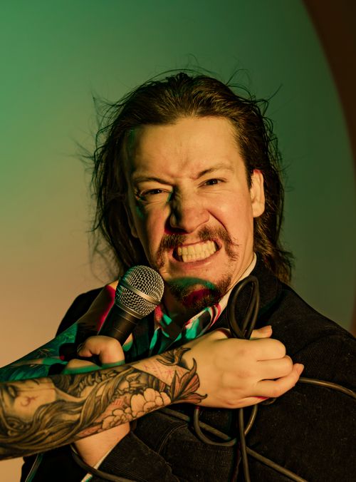 Free Dynamic portrait of a male singer holding a microphone, showing emotion with a detailed arm tattoo visible. Stock Photo