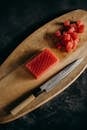 木制砧板上，新鲜金枪鱼块与刀的特写，非常适合制作亚洲美食