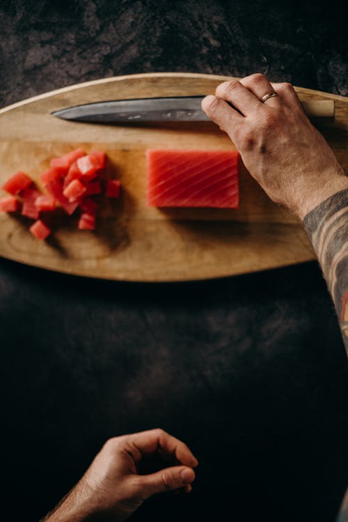 Person Holding Knife Slicing Red Fruit
