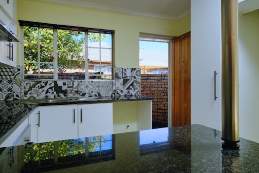 Contemporary kitchen interior with patterned tiles and view of garden.