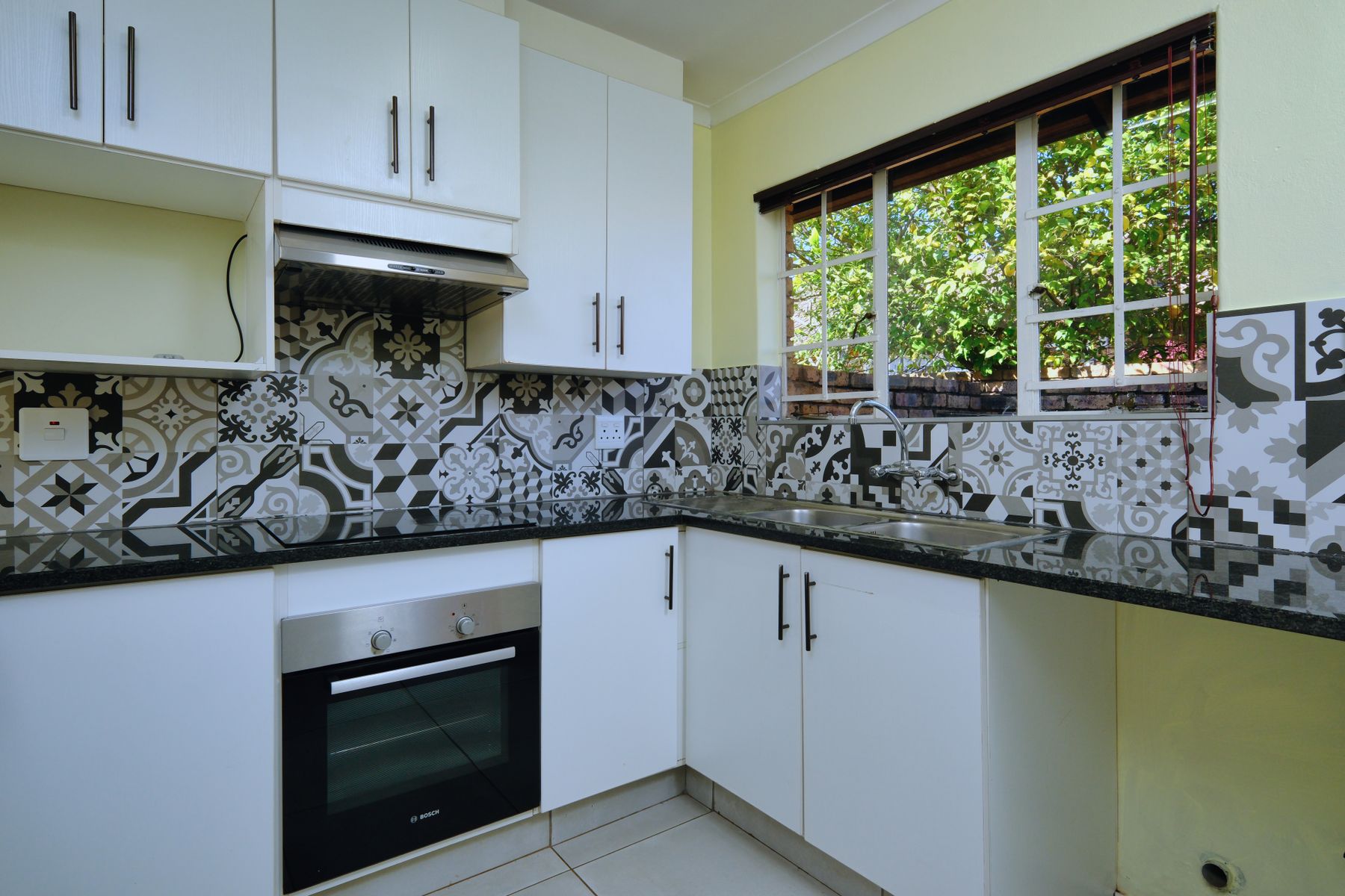 Contemporary kitchen with an expressive black and white patterned backsplash behind a simple worktop