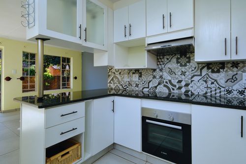Free Sleek modern kitchen interior with patterned backsplash and white cabinets. Stock Photo