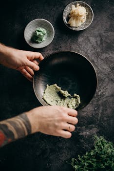 将新鲜的芥末放入深色陶瓷碗中，配以姜和香草，双手捕捉传统的日本烹饪时刻