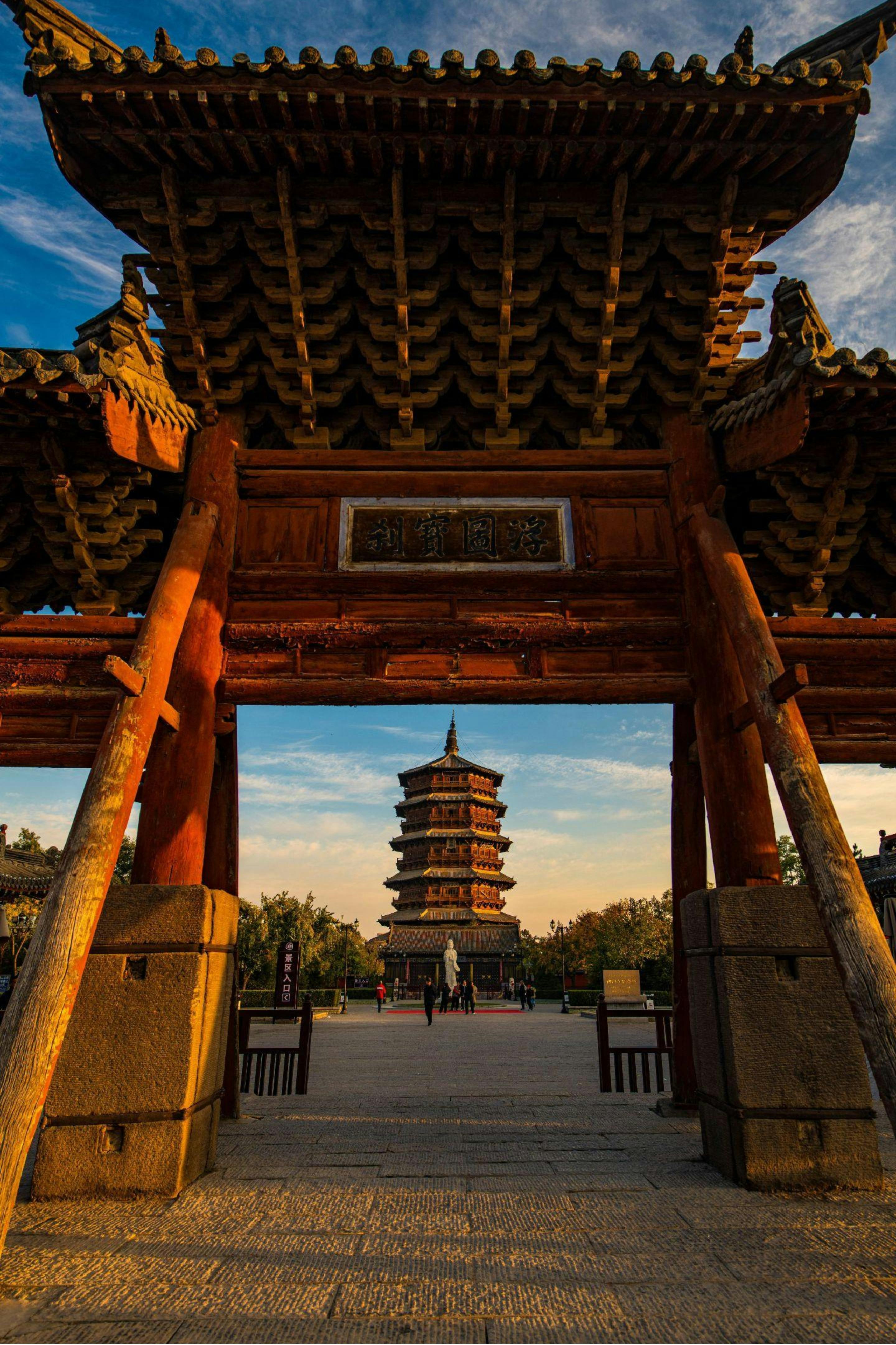 A stunning view of an ancient wooden pagoda framed by a traditional gate in Shanxi Province, China.