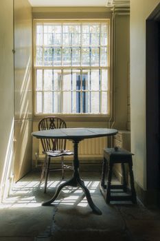A warm, sunlit room in London featuring vintage furniture by a window, creating a serene ambiance.