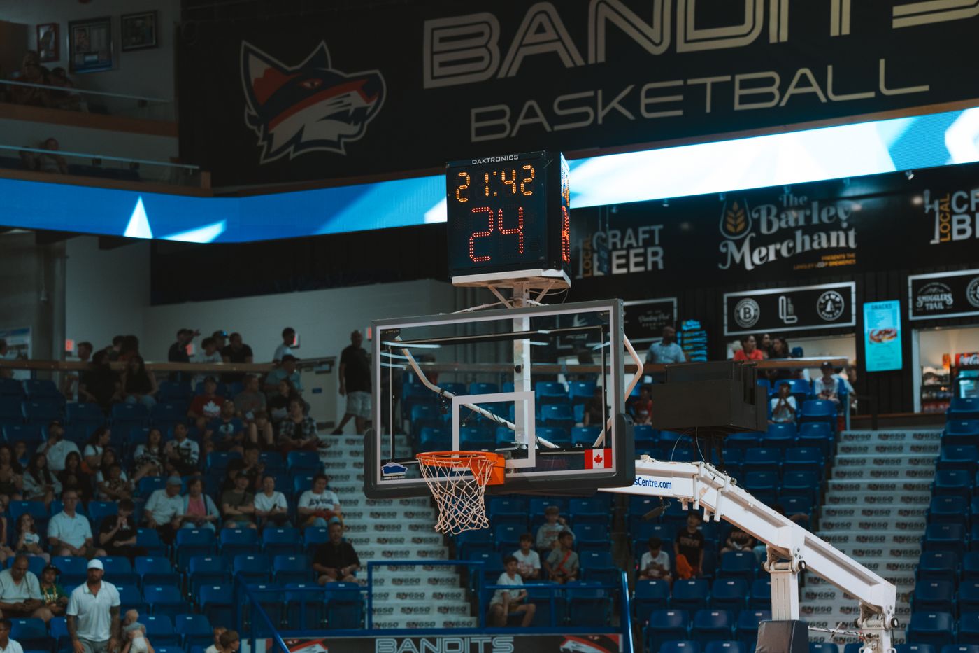 Close-up of a basketball hoop inside a packed stadium with a scoreboard and audience
