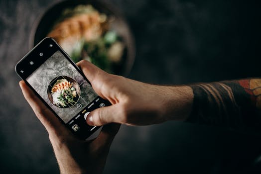 A person photographs a delicious Japanese dish using a smartphone, highlighting modern food photography.