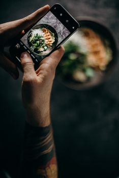 在光线昏暗的环境里，一个人用智能手机拍摄了一道日本菜肴