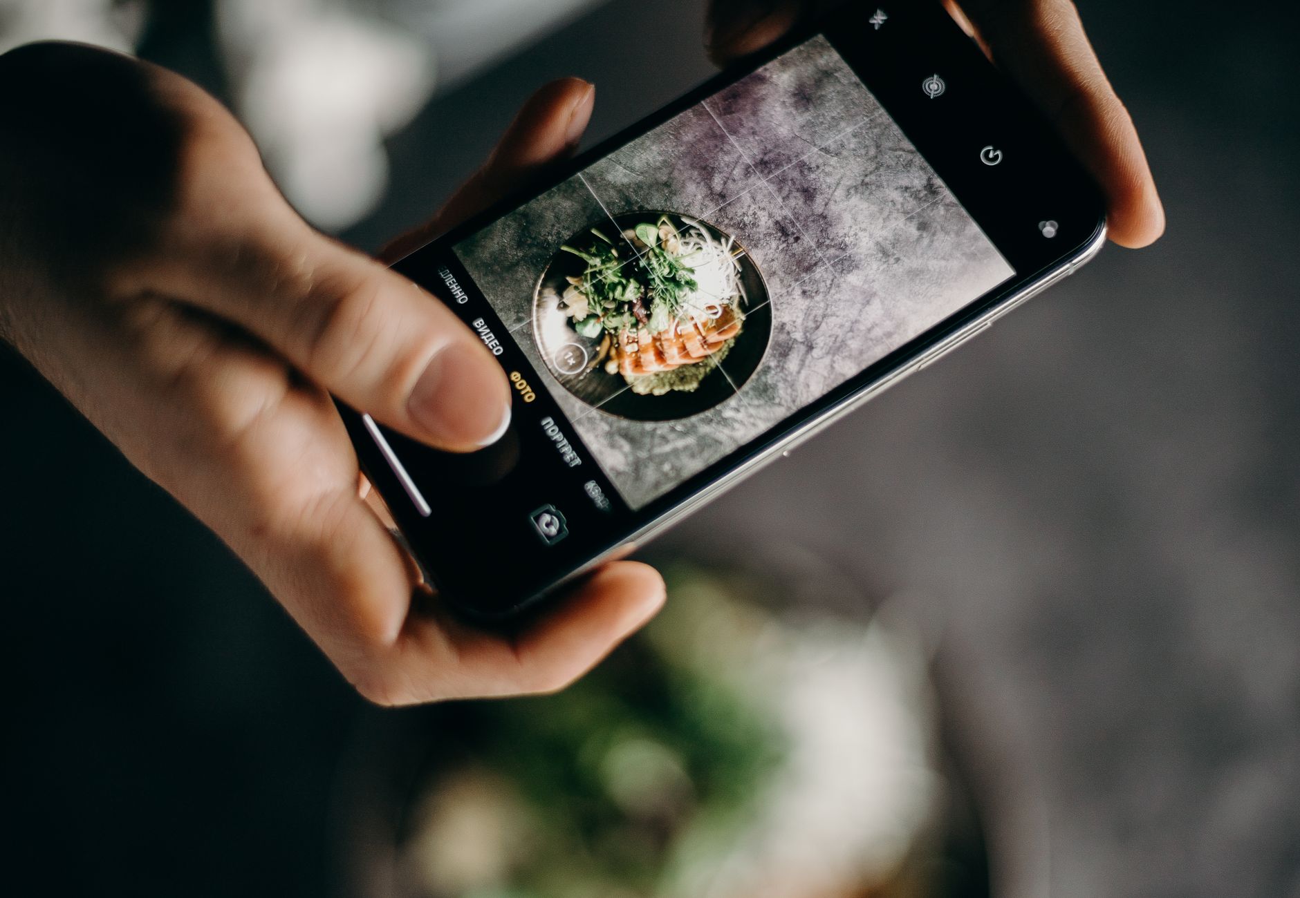 Person photographing delicious Asian dish with a smartphone in a creative setting.
