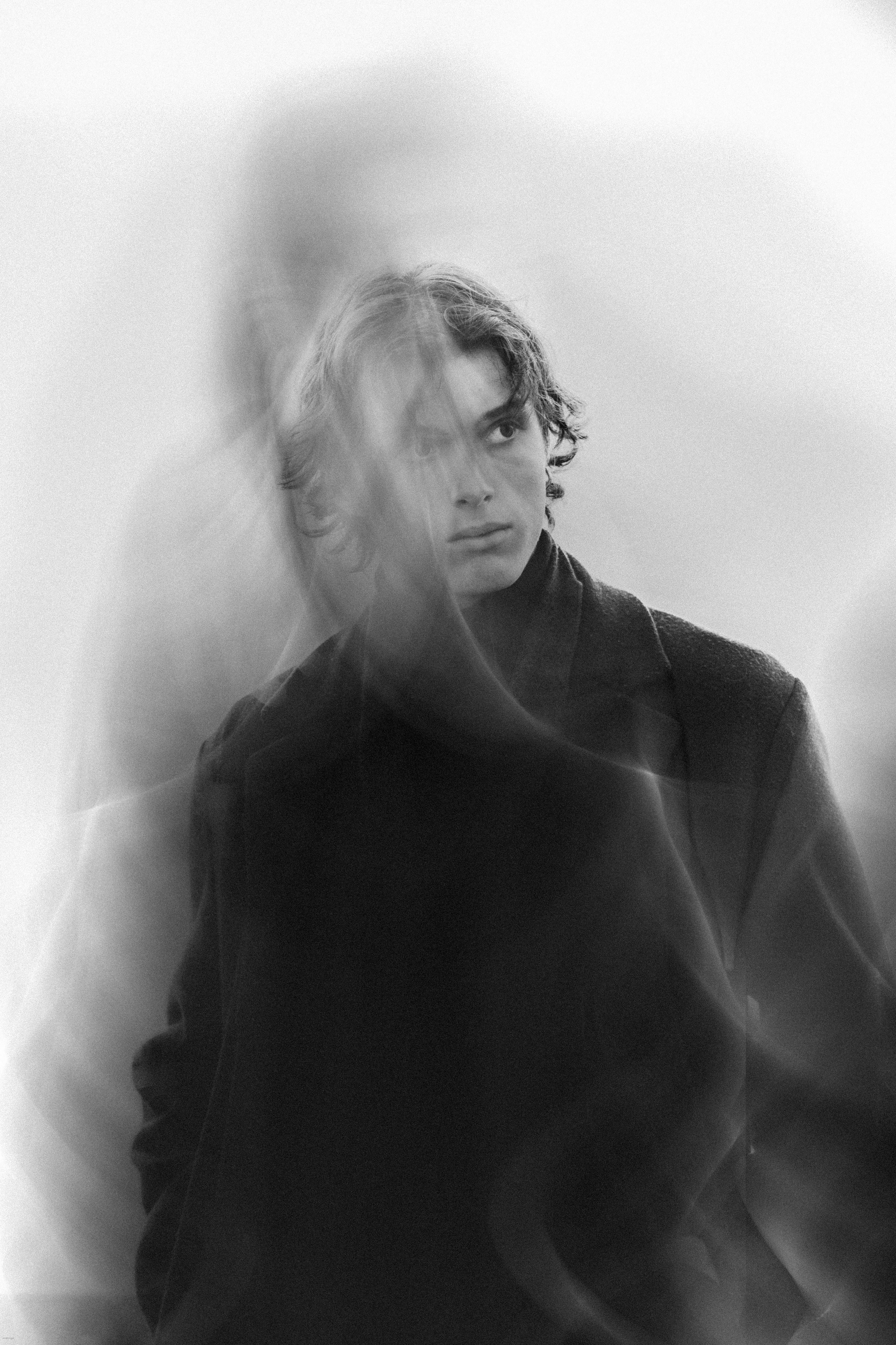 Black and white artistic portrait showcasing a man in motion blur adding a mysterious and creative effect.