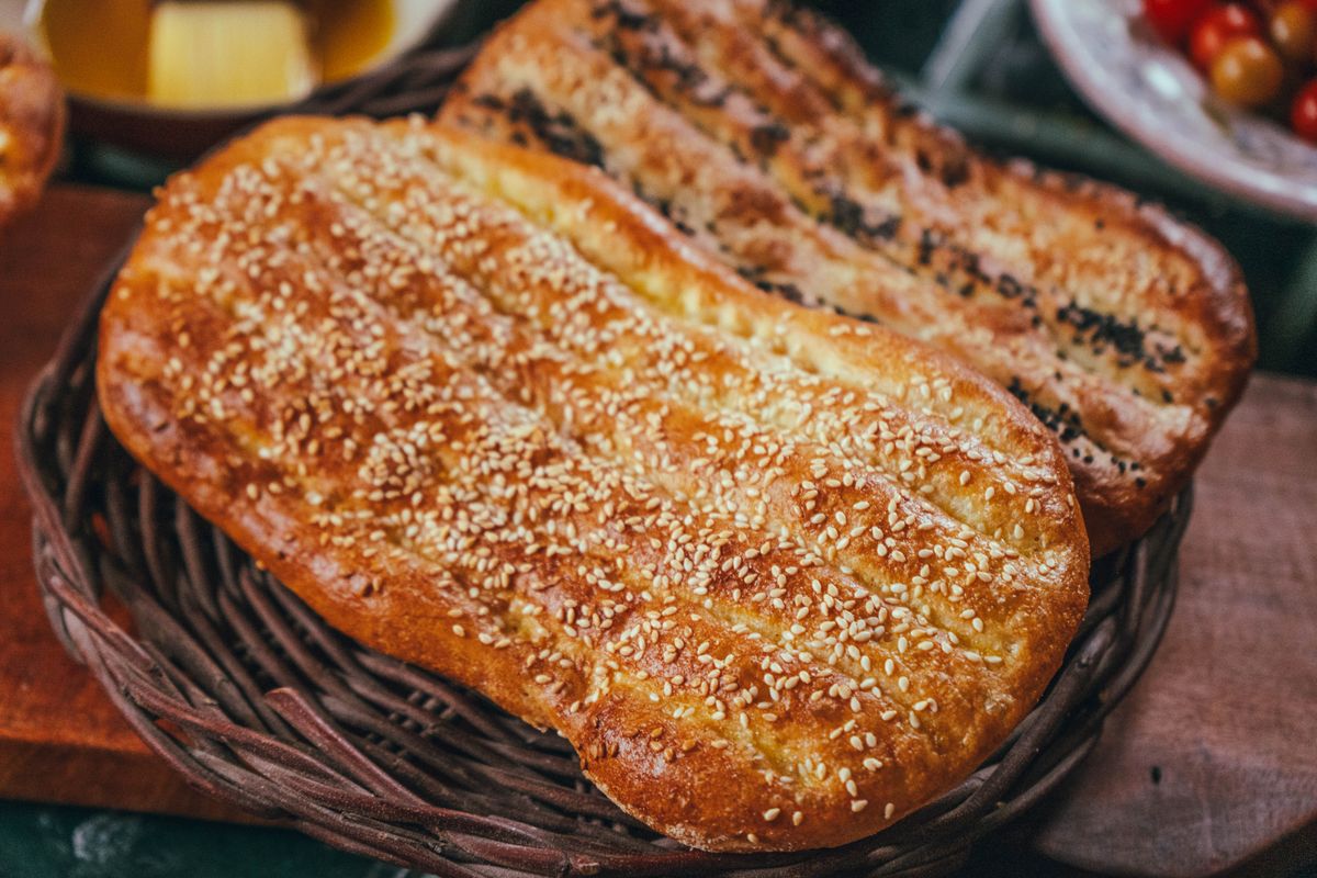 Long oval barbari flatbreads with grooved golden tops and sesame seeds in a wicker basket