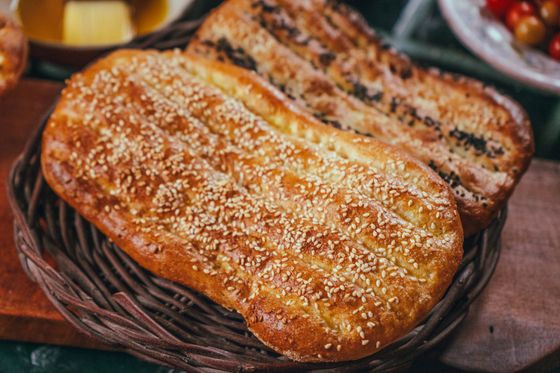 Long oval barbari flatbreads with grooved golden tops and sesame seeds in a wicker basket