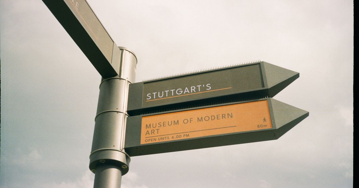 Signpost directing to a museum of modern art under an overcast sky