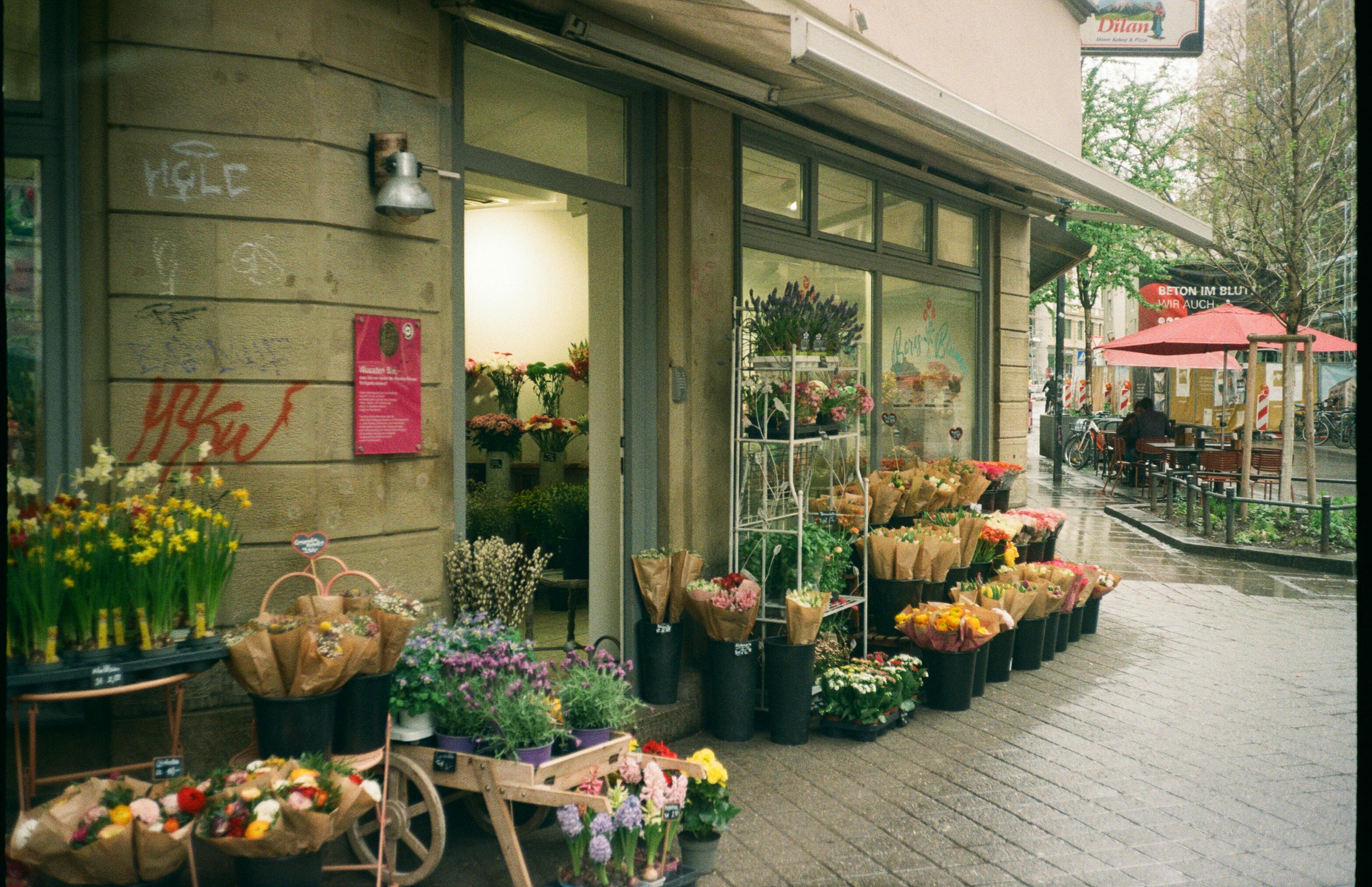 A delightful display of flowers outside a shop in rainy Stuttgart, showcasing vibrant floral colors.