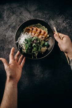 一道以平放风格呈现的亚洲三文鱼菜肴，配有蔬菜和面条，美味可口