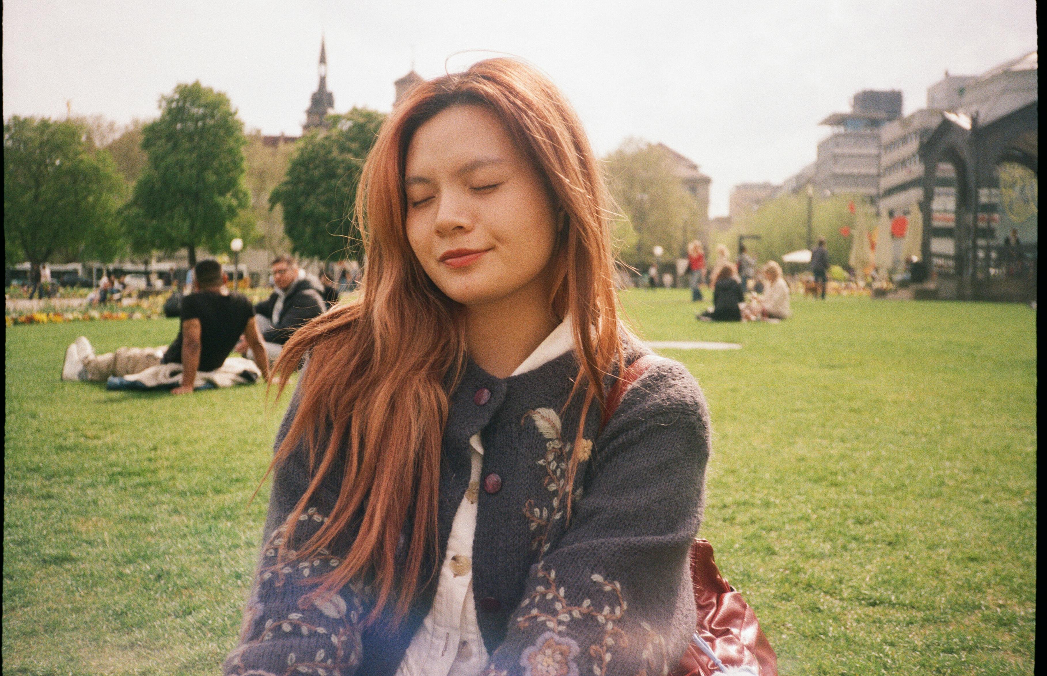 A young woman enjoys a peaceful moment in a Stuttgart city park, surrounded by greenery.