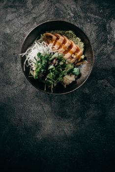 A beautifully plated salmon poke bowl with fresh greens on a textured surface.