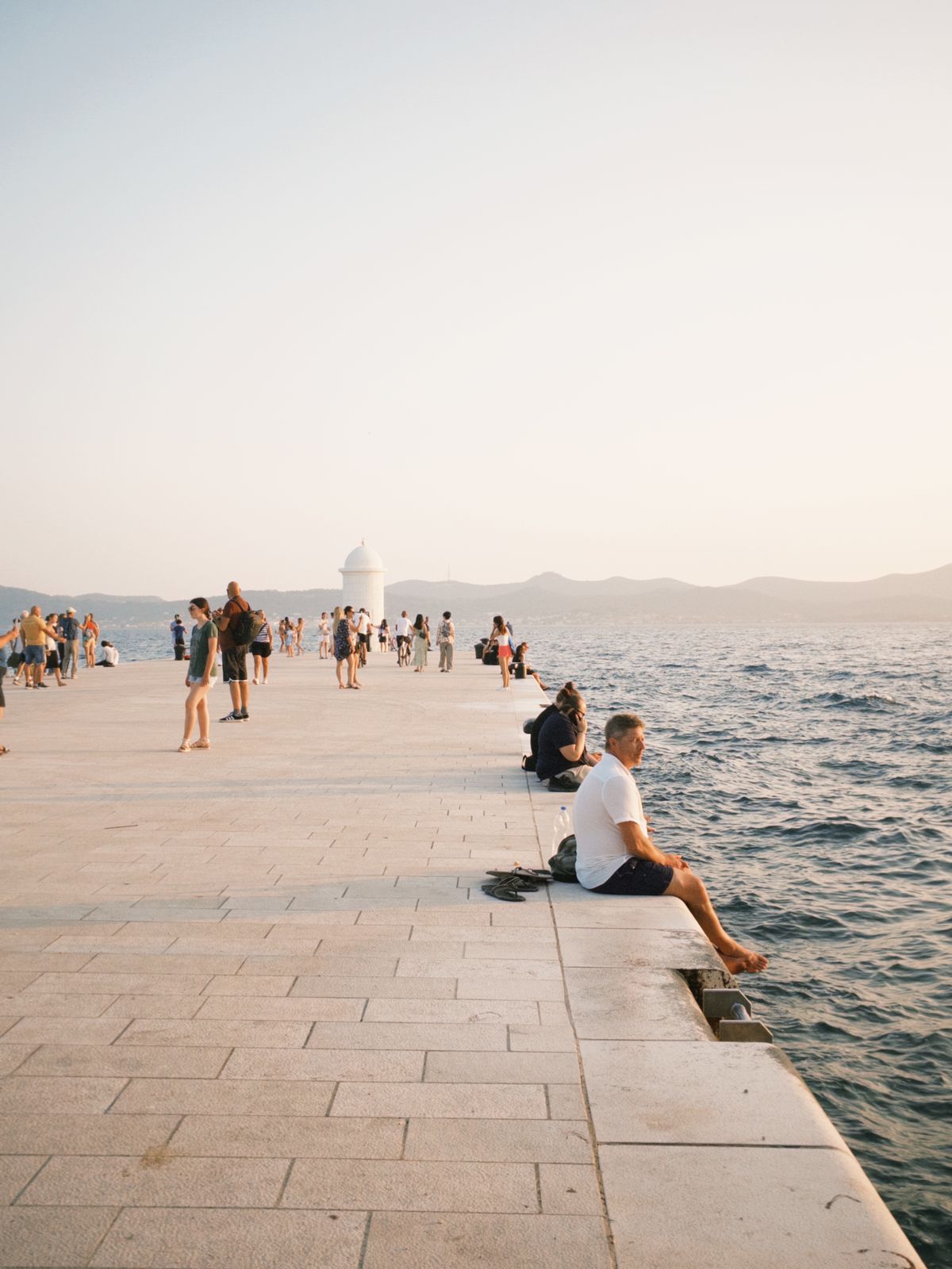 Zadar - turiști pe promenadă la apus, aproape de plaja de oraș
