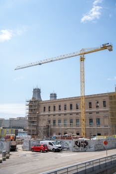 A historic building undergoing renovation with a crane under a clear blue sky.