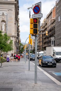 Urban view of a busy Barcelona street with traffic lights and pedestrians on a sunny day.